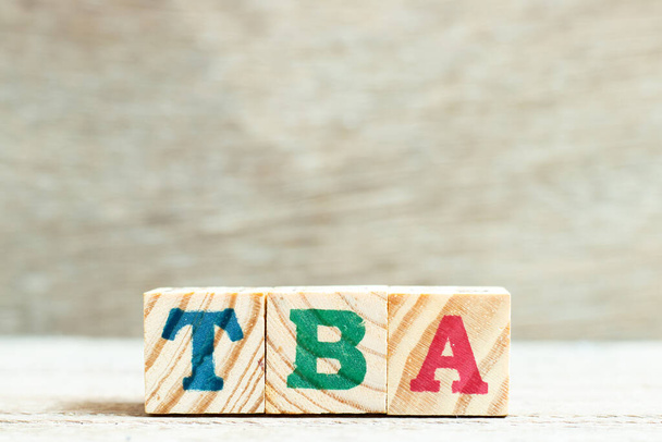 Letra alfabética em palavra TBA (abreviatura a anunciar) sobre fundo de madeira - Foto, Imagem
