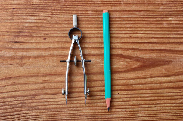 gros plan de l'ensemble des outils pour le dessin, y compris diviseur en métal et crayon vert isolé sur fond en bois
 - Photo, image