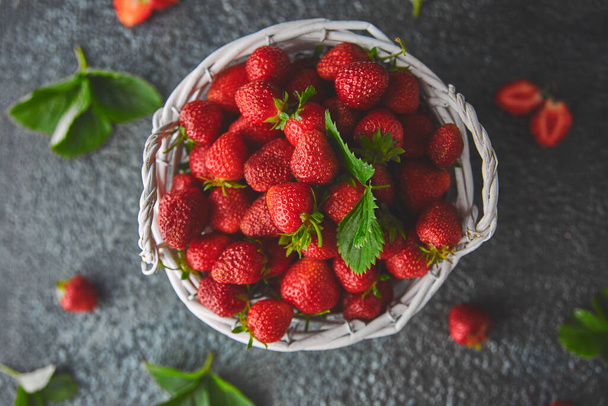 Rijp rode aardbeien op zwarte achtergrond, aardbeien in witte mand. Verse aardbeien. Mooie aardbeien. Dieetvoeding. Gezond, veganistisch. Bovenaanzicht. Vlakke plaat. - Foto, afbeelding
