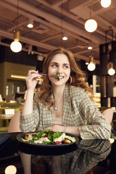 Портрет молодой красивой улыбающейся женщины, питающейся здоровой пищей в интерьере кафе
 - Фото, изображение
