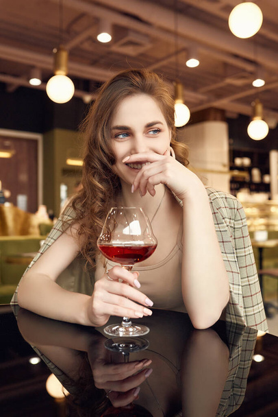 Portrét elegantní krásné brunetky se sklenkou červeného vína v interiéru restaurace - Fotografie, Obrázek