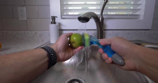 Une perspective personnelle unique d'un homme lavant une poire dans l'évier de la cuisine. Il a été fortement recommandé de laver les aliments avant de manger pendant la pandémie de COVID-19 de 2020.
.   - Séquence, vidéo