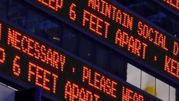 Closeup άποψη ενός Times Square ticker υπενθυμίζει στους πεζούς να κρατήσει 6 πόδια μακριά ο ένας από τον άλλο. Η κοινωνική απόσταση ήταν μια κοινή πρακτική για να επιβραδύνει την εξάπλωση της COVID-19 κατά τη διάρκεια της πανδημίας του 2020.   - Πλάνα, βίντεο