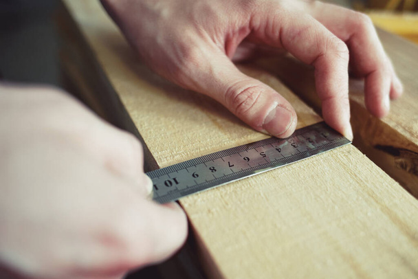 建設と修理。男性の手線は木製の板の幅を測定します。クローズアップツールで手。生産管理. - 写真・画像
