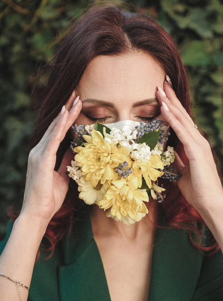 Porträt einer schönen Frau in Schutzmaske mit Blumen. - Foto, Bild