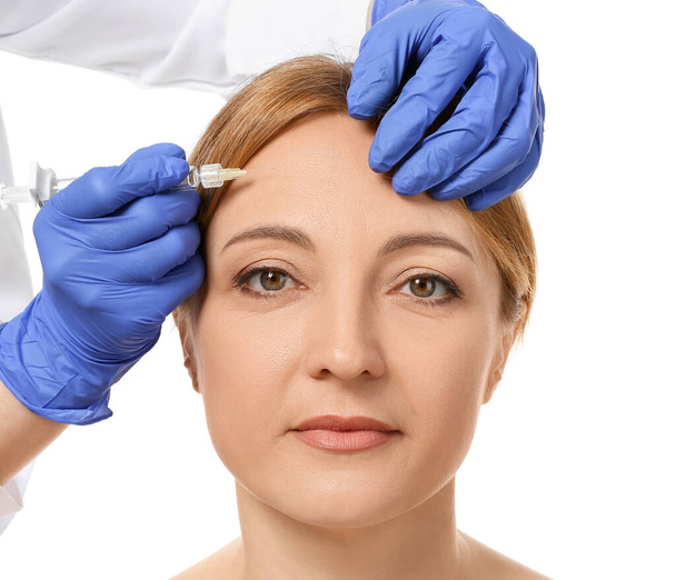 Woman receiving filler injection against white background - Foto, Imagen
