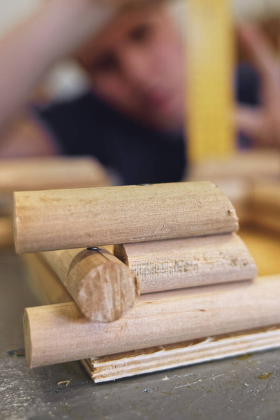 Egy férfi ács egy fával dolgozik egy asztalosműhelyben. Csinálok egy modellt egy faházról. - Fotó, kép