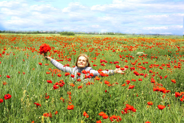 Glücklich reisende Frauen mit einem Strauß roter Mohnblumen auf der Mohnwiese im Grünen. Mohnfeld zur Sommerzeit. - Foto, Bild
