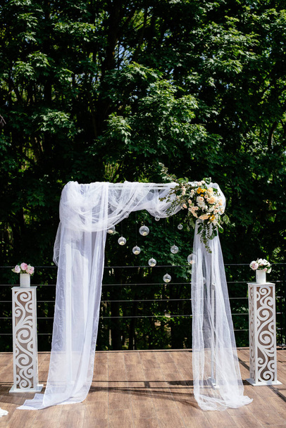 El área fotográfica al aire libre es una decoración elegante de la boda. Arco de boda, decorado con flores, mini florales. Hermosa ceremonia de boda al aire libre lugar para la celebración
. - Foto, Imagen