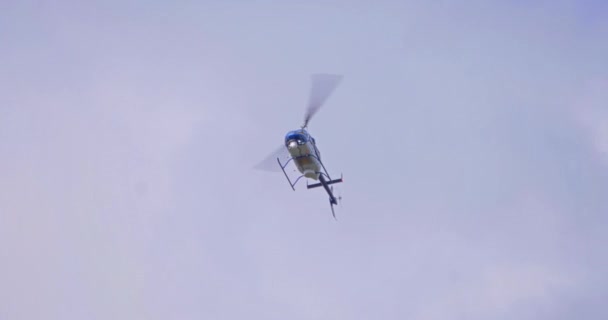 A slow motion stabilized view looking up at a news or police helicopter. Identifiable markings obscured. Shot at 50% speed.   - Footage, Video