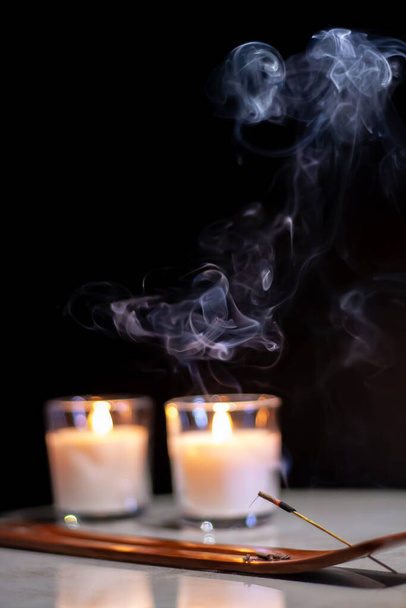 θυμίαμα καπνού στικ θυμίαμα με μαύρο φόντο και μη εστιασμένα ζεστά κεριά - Φωτογραφία, εικόνα
