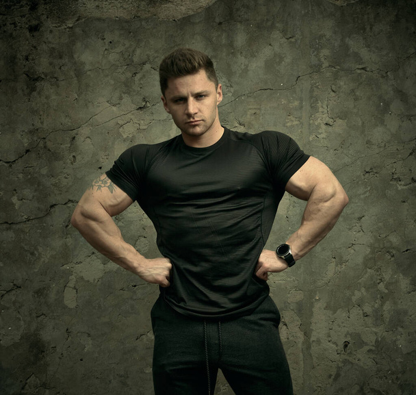 Attractive athletic portrait of a guy in a sports t-shirt. Beautiful portrait of a fitness model. The concept of fitness, health, lifestyle. Sportswear. - Photo, Image