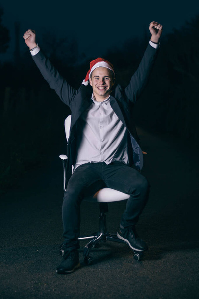 クリスマス休暇の到来を祝うサンタの帽子をかぶっている幸せな若いビジネスマン - 写真・画像