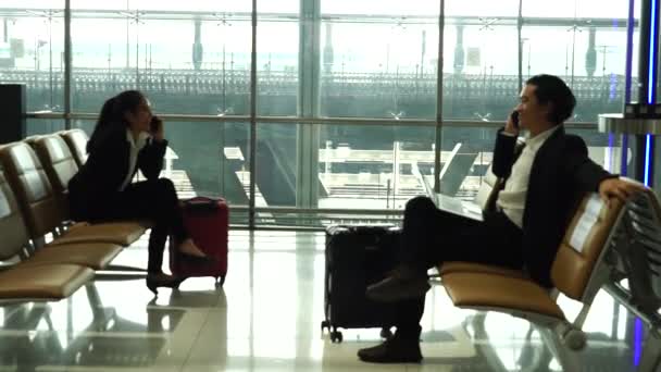 Backpacker matkustajat Aasian naiset yllään naamarit covid 19 sairauksien ehkäisy ja istuu, luoda sosiaalisen etäisyyden odottaessaan yhteyden lentokoneeseen lentokentällä.Loma ja matka käsite - Materiaali, video