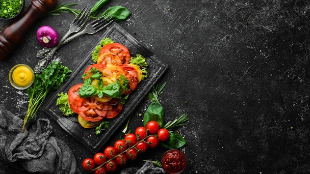 Salad of fresh tomatoes and basil on a black stone plate. Top view. Free copy space. - Fotoğraf, Görsel