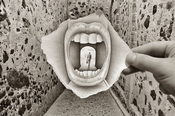 Image mixte montrant un morceau de papier tenu à la main avec un dessin au crayon représentant une bouche immense et grande ouverte avalant une silhouette d'homme marchant avec une rue et des murs texturés en arrière-plan. - Photo, image