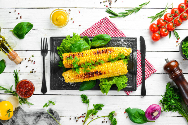 Baked grilled corn with spices and salt on a black stone plate. Top view. Free copy space. - Foto, imagen