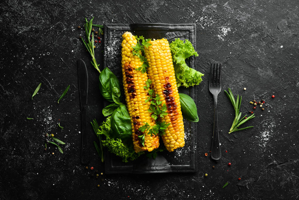 Baked grilled corn with spices and salt on a black stone plate. Top view. Free copy space. - Фото, изображение