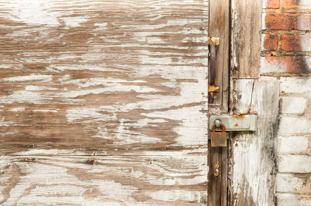 Una vecchia porta coperta da pannelli di compensato e vernice sfalsata su un vecchio magazzino urbano è fissata da una serratura arrugginita; utile per lo sfondo della texture
 - Foto, immagini