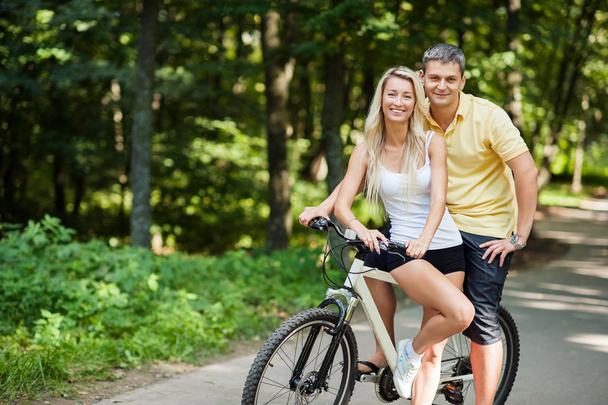 Atractiva pareja feliz en una bicicleta en un campo
 - Foto, imagen