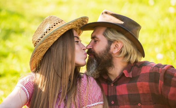 True feelings. Enjoying life. Love and harmony. Bearded cowboy in hat kissing adorable girlfriend. Couple in love. Romantic kiss. Happy couple ranch owners. Married and happy. Rustic people in love - 写真・画像