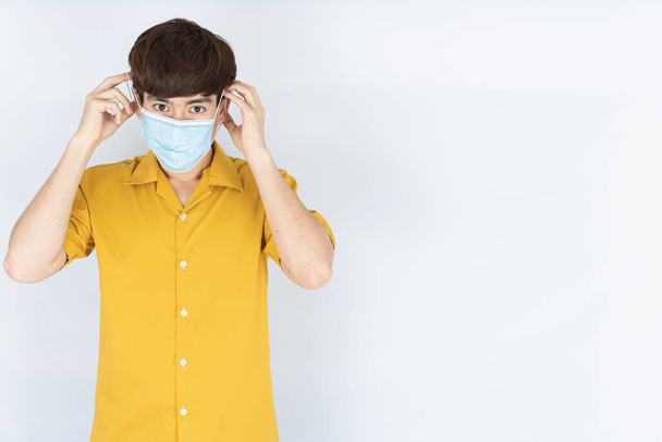 Asijské hezký šťastný hipster muž na sobě lékařské ochranné masky obličeje pro ochranu koronaviru, filtr prach PM 2.5 a chlad na bílém pozadí - Fotografie, Obrázek