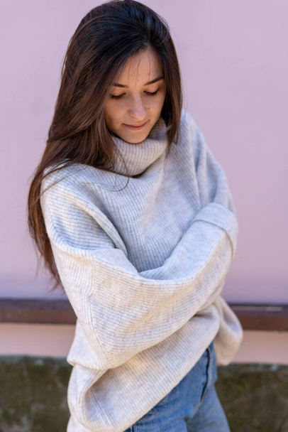 Beautiful stylish young woman with fashionable knitted women's sweater oversize near the pink wall - Foto, Imagen