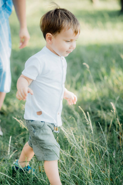little stylish blond  boy with blue eyes dressed in a white shirt playing outside - Zdjęcie, obraz