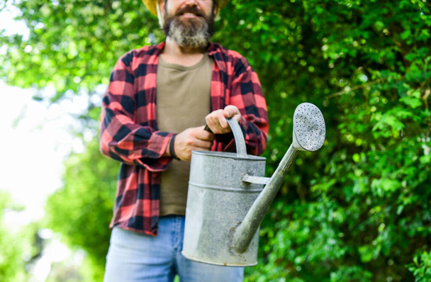 Man using a big watering can for planting. pour the water. man with watering can. gardening and watering plants. agriculture and tough work concept. Gardening or planting concept - Fotó, kép
