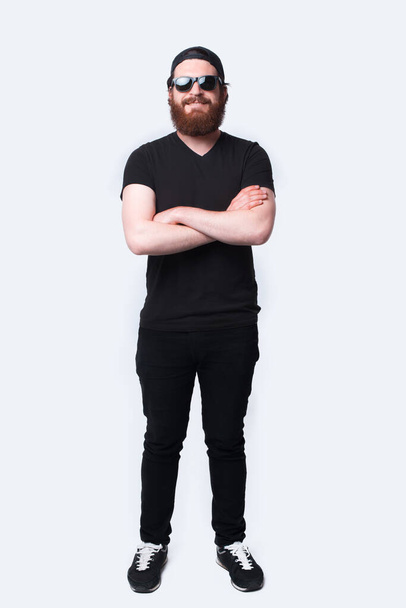 portret van een man met baard die zelfverzekerd kijkt naar de camera met gekruiste armen - Foto, afbeelding