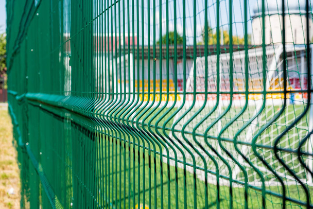 Grilla protectora verde de cerca. El patrón de una rejilla protectora para un campo de deportes. Fondo deportivo
. - Foto, imagen