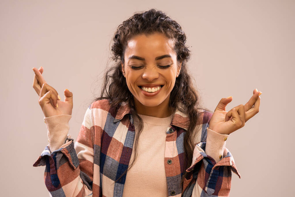 Stúdió lövés portré gyönyörű boldog afro-amerikai etnikai nő ujjait keresztbe. - Fotó, kép