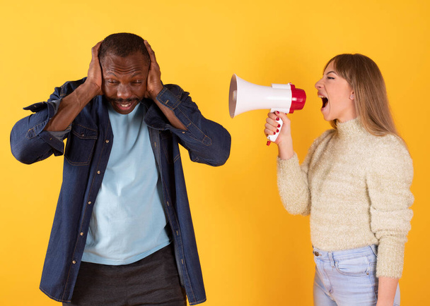 An excited man and woman screaming with a megaphone, yellow background - Photo, Image