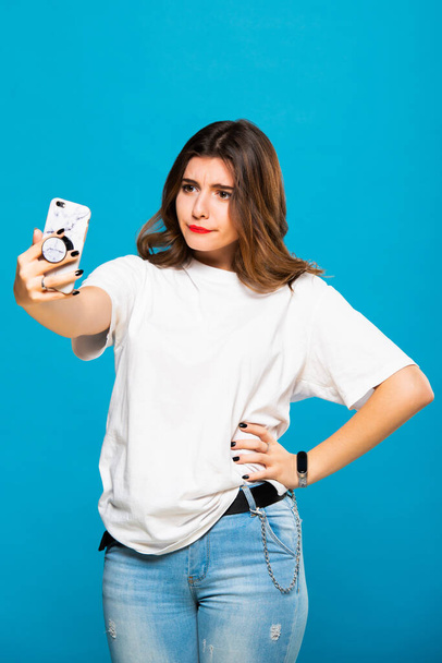 Cute funny girl student teenager makes selfie on a cell phone. Emotions and grimaces. - Foto, Imagem