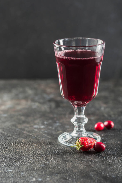 The concept of a summer refreshing drink from red berries: berry Morse of fresh strawberries and cranberries is a great drink to quench your thirst on a black background with a copy space. Vertical orientation. - 写真・画像