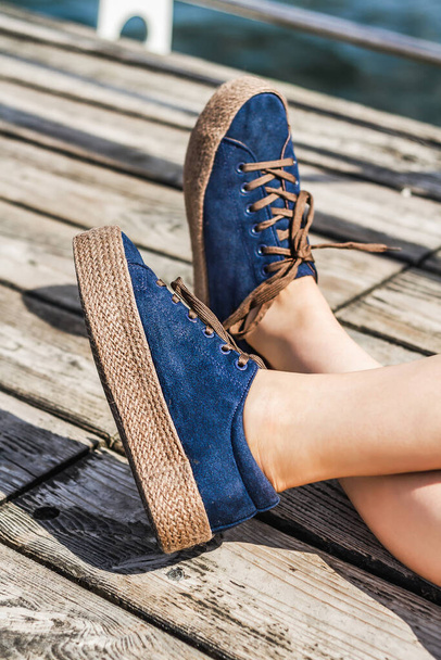 Blaue Espadrilles aus Wildleder für Mädchen und Frauen. Frauenbeine in bequemen modischen Schuhen auf einem hölzernen Hintergrund. Stilvolle Schuhe Mode SS '20 - Foto, Bild