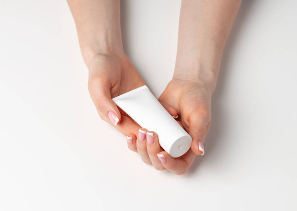 Female hand holding cosmetic bottle on white - Foto, immagini