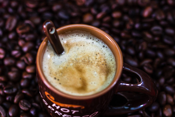 Close-up van kopje koffie, gebrande koffiebonen op rode achtergrond, koffie concept, close-up koffie foto - Foto, afbeelding