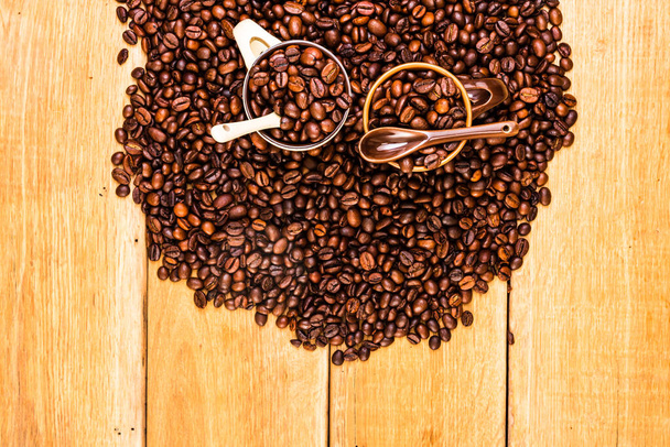 Detail pražených kávových zrn a šálku kávy na dřevěném pozadí, horní pohled, kopírovací prostor pro text, close up coffee photo - Fotografie, Obrázek