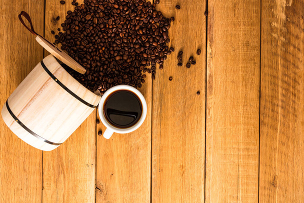 filiżanka kawy, palona ziarna kawy na drewnianym tle, drewniana lufa kawy widok z góry, miejsce na tekst, zbliżenie kawy zdjęcie - Zdjęcie, obraz