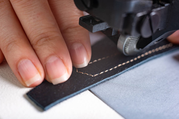 girl sews on a sewing machine scribbles fabric and leather making a product - 写真・画像