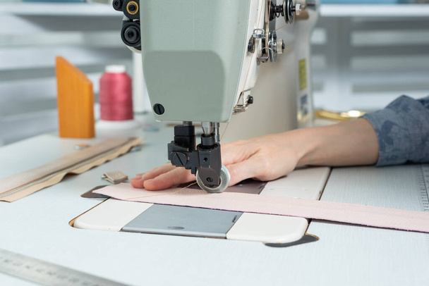 女の子はミシンの上に縫い付けの布と革で製品を作る - 写真・画像
