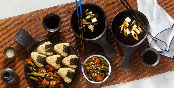 banner of Japanese breakfast with miso soup, onigiri and vegetables in sweet and sour sauce. Typical traditional morning food - Foto, afbeelding