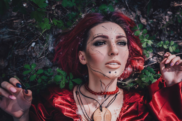 Girl in red and red hair in the form of a druid in apple trees - Foto, Imagem