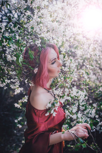 Girl in red and red hair in the form of a druid in apple trees - Photo, Image