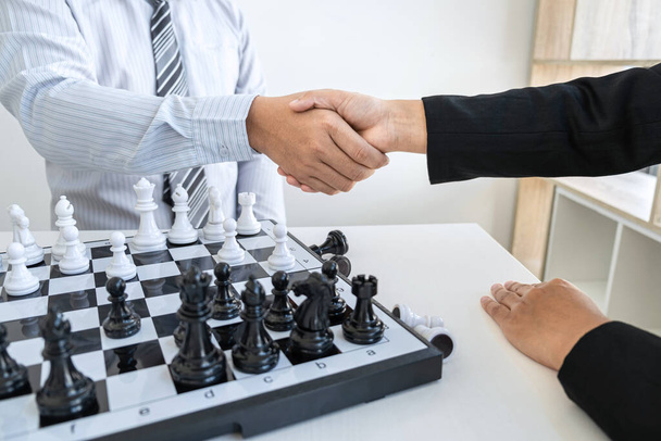 Liikemies ja liikenainen kättelee pelattuaan shakkia ja harkittuaan strategian kaatumista kaataa vastakkaisen joukkueen ja kehitysanalyysin voiton ja onnistuneen. - Valokuva, kuva