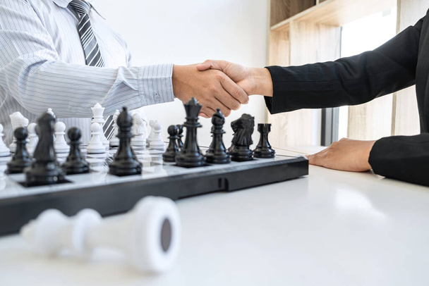 Επιχειρηματίας και επιχειρηματίας χειραψία μετά το παιχνίδι σκάκι και τη σκέψη για συντριβή στρατηγικής ανατρέψει την αντίθετη ομάδα και την ανάλυση ανάπτυξης για τη νίκη και την επιτυχία. - Φωτογραφία, εικόνα