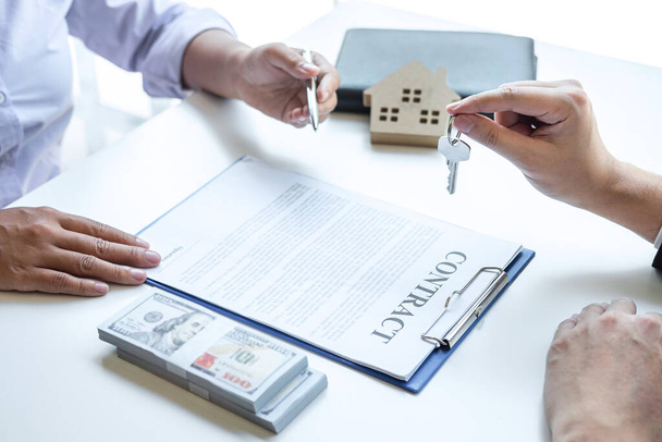 Immobilienmakler übergibt dem Kunden Hausschlüssel nach Unterzeichnung des Vertrages Immobilien mit genehmigtem Hypothekenantragsformular, betreffend Hypothekendarlehen und Hausversicherung. - Foto, Bild