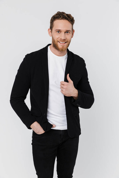 Image of unshaven pleased man in jacket smiling and posing on camera isolated over white background - Fotografie, Obrázek