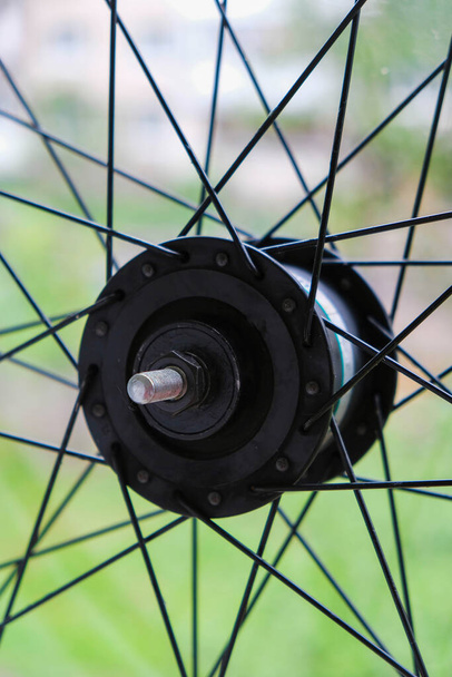 後ろの自転車の車輪の一部には、自然な背景にスポークがあります。自転車修理。垂直画像. - 写真・画像